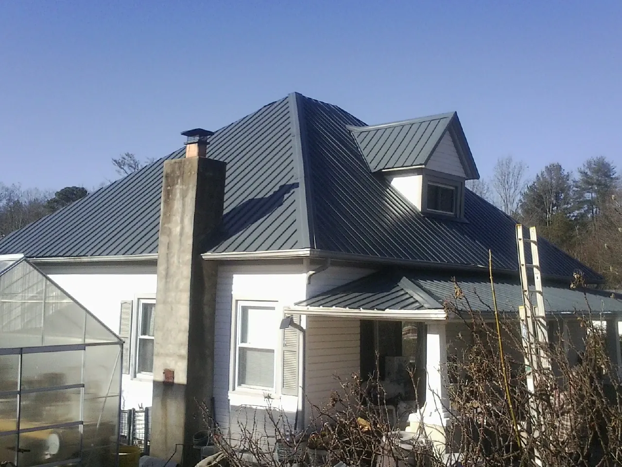 Dark blue standing seam metal roof on a white farmhouse with dormer — Slate & Tile Roof Repair by Roofing Brothers in Port Orford