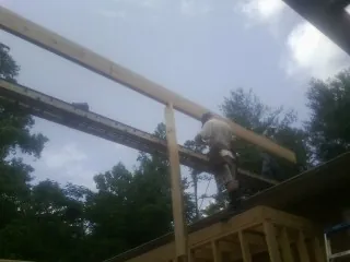 Carpenter setting a ridge beam over a new addition frame — Ice Dam Removal by Roofing Brothers in Port Orford