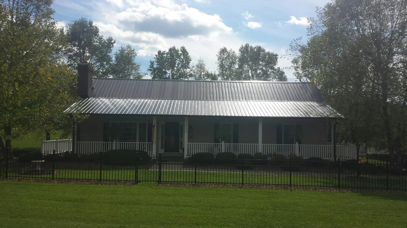 Gray metal roof on a brick ranch with a full width front porch — Gutter Guard Installation work by our crew in Port Orford