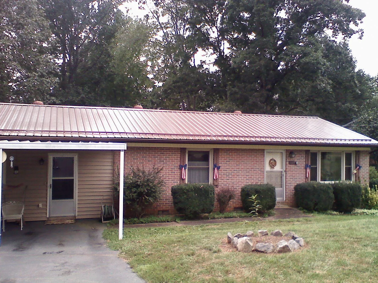 Bronze metal roof and carport on a brick ranch home — Roof Repair work by our crew in Port Orford
