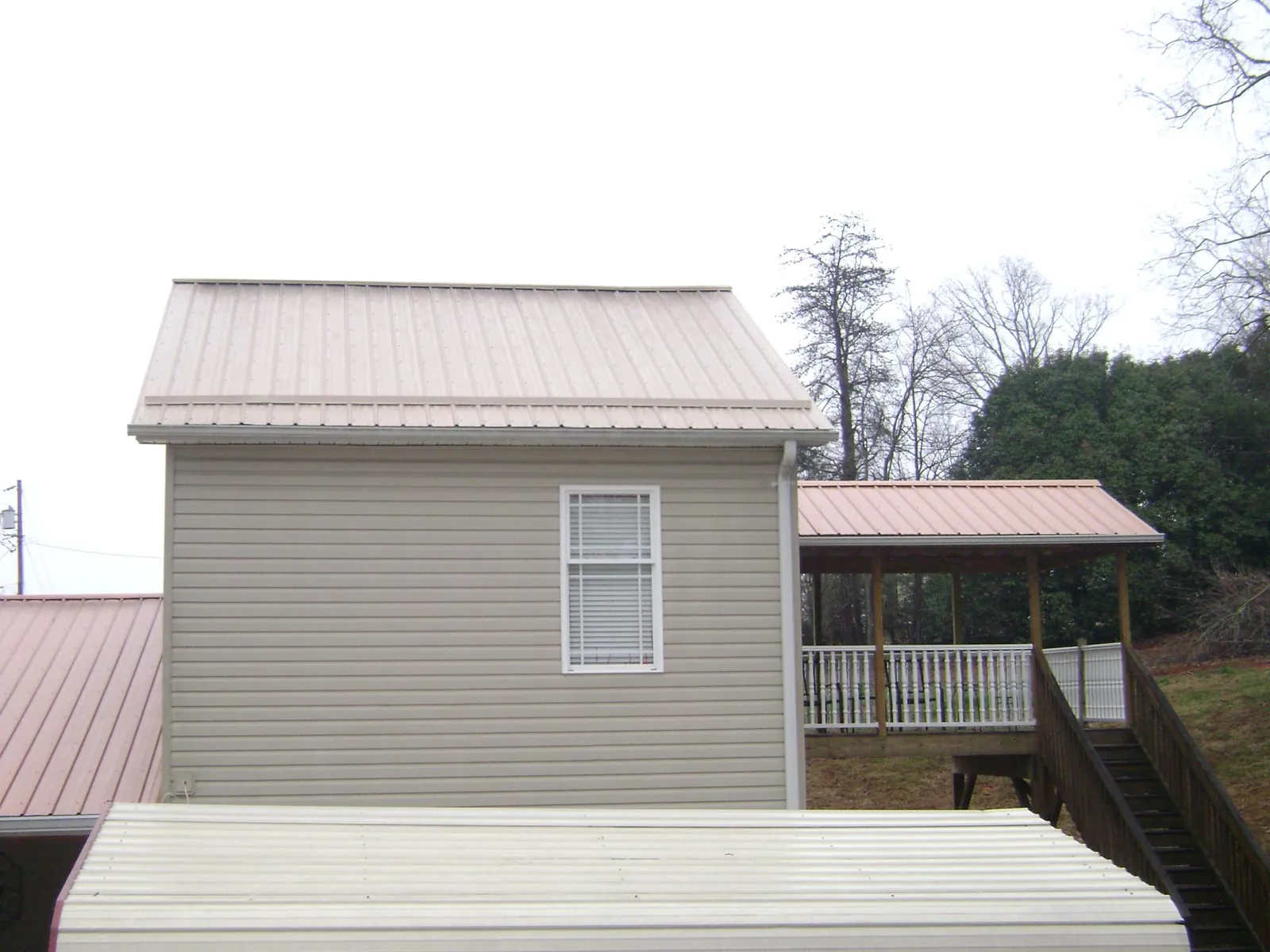 Tan metal roofs on a two story addition and attached porch, from a Roof Replacement job in Port Orford