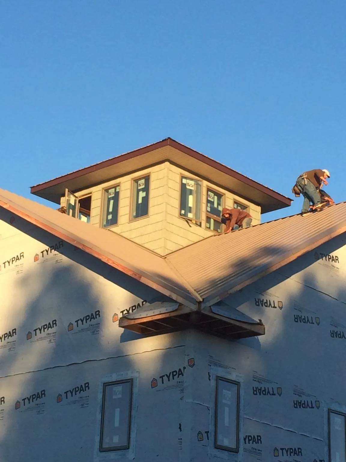 Roofers working around a rooftop cupola on a new metal roof at sunset — Roof Waterproofing in Port Orford by Roofing Brothers